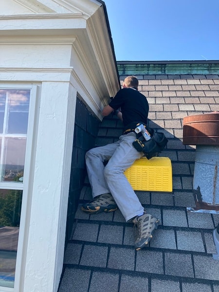 A man fixes a roof to exclude raccoons